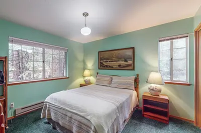 a bedroom with green walls and a bed and two windows at Travelers Rest in Shaver Lake Heights