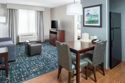 a hotel room with a table and chairs and a living room at Homewood Suites by Hilton Fresno Airport/Clovis in Clovis
