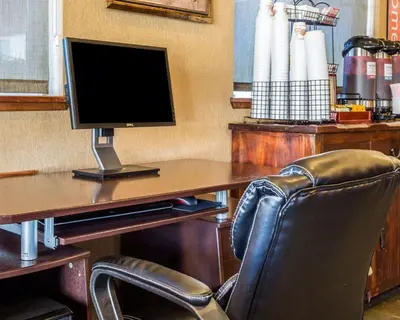 a computer monitor sitting on a desk with a chair at Quality Inn Lone Pine near Mount Whitney in Lone Pine