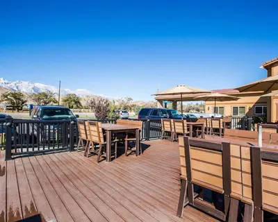 a wooden deck with tables and chairs and umbrellas at Quality Inn Lone Pine near Mount Whitney in Lone Pine