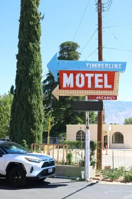 a sign for a motel with a car parked in front at Timberline Motel in Lone Pine