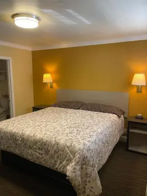 a bedroom with a bed and two lamps on the wall at Timberline Motel in Lone Pine