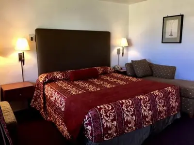 a hotel room with a bed and a couch at Maple Inn and Suites Los Banos in Los Banos