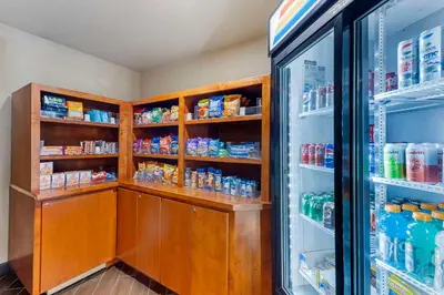 a kitchen with a refrigerator and shelves of food at Comfort Inn & Suites Rocklin - Roseville in Rocklin