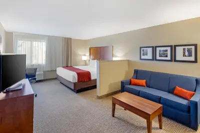 a hotel room with a bed and a blue couch at Comfort Inn & Suites Rocklin - Roseville in Rocklin