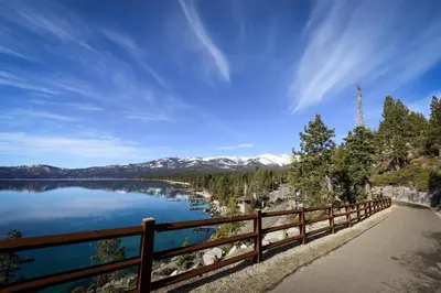 a wooden fence next to a lake with snow covered mountains at McCloud 137 in Incline Village