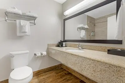 a bathroom with a toilet and a sink and a mirror at Best Western Kettleman City Inn & Suites in Kettleman City