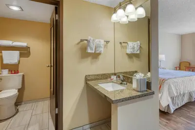 a bathroom with a sink and a toilet and a bed at SureStay Plus Hotel by Best Western Reno Airport in Reno