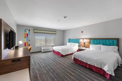a hotel room with two beds and a flat screen tv at Hampton Inn & Suites Madera in Madera