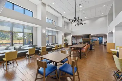 a waiting room with tables and chairs in a building at Hampton Inn & Suites Madera in Madera