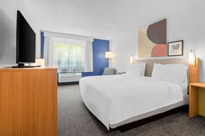 a bedroom with a large white bed and a flat screen tv at Spark by Hilton Modesto in Modesto
