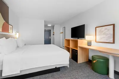 a hotel room with a bed and a desk with a television at Spark by Hilton Modesto in Modesto