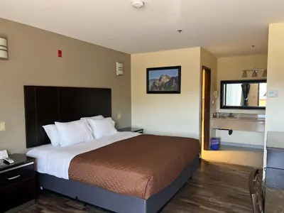 a hotel room with a large bed and a bathroom at Yosemite Sierra Inn in Oakhurst