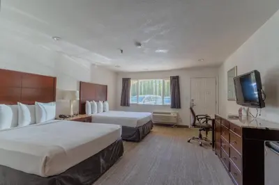 a hotel room with two beds and a flat screen tv at The Yosemite Inn in Mariposa