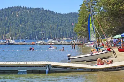 a group of people in the water at a beach with a boat at Forest Falls in Shaver Lake