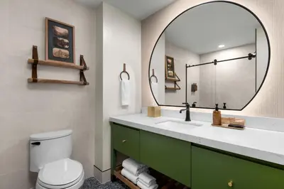 a bathroom with a green vanity and a mirror at The Inelle, Oakhurst Yosemite, a Tribute Portfolio Hotel in Oakhurst