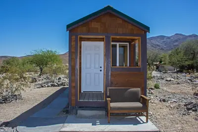 a wooden outhouse with a chair and a door at Panamint Springs Motel & Tents in Panamint Springs