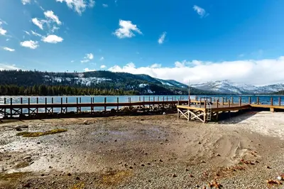 a dock on a beach next to a body of water at Donner Lake Retreat in Donner Pines Tract