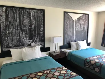 a hotel room with two beds and a painting on the wall at Super 8 by Wyndham Selma/Fresno Area in Selma