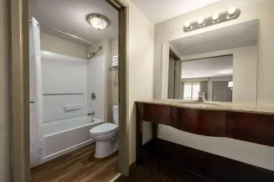 a bathroom with a toilet and a sink and a mirror at Days Inn by Wyndham Fresno South in Fresno