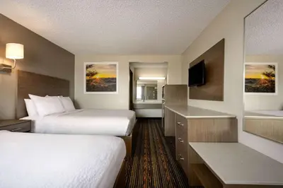 a hotel room with two beds and a television at Days Inn by Wyndham Fresno South in Fresno