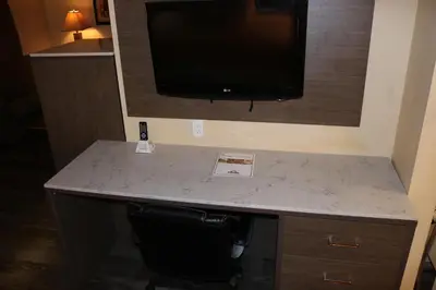 a desk in a hotel room with a television on the wall at Days Inn by Wyndham Fresno South in Fresno