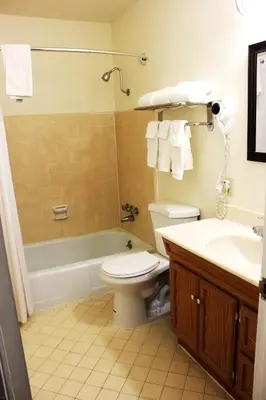 a bathroom with a toilet and a tub and a sink at Rodeway Inn Near University-Gateway to Yosemite in Merced