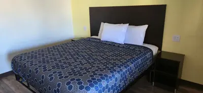 a bedroom with a bed with a blue comforter and pillows at Grapevine Inn in Lodi