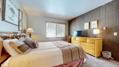 a bedroom with a large bed and a television at Chateau De Montagne #1 Condo in Mammoth Lakes