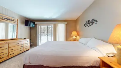 a bedroom with a large white bed and a television at Chateau De Montagne #15 Condo in Mammoth Lakes