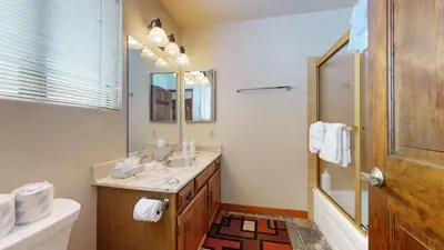 a bathroom with a sink and a mirror and a tub at Snowflower #26 Condo in Mammoth Lakes