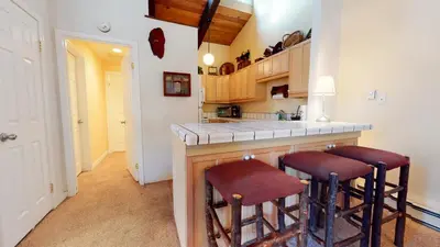 a kitchen with a counter and two stools at a bar at Chateau De Montagne #23 Condo in Mammoth Lakes