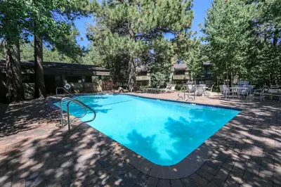 a large blue swimming pool with tables and chairs at Chateau De Montagne #23 Condo in Mammoth Lakes