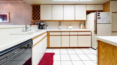 a kitchen with white cabinets and a red rug at Bridges #105 Condo in Mammoth Lakes