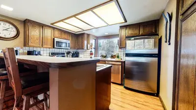 a kitchen with a refrigerator and a clock on the wall at Forest Creek #28 Condo in Mammoth Lakes