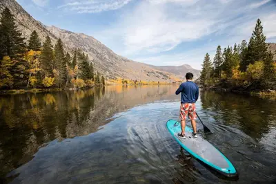a man is standing on a paddle board in the water at Forest Creek #28 Condo in Mammoth Lakes