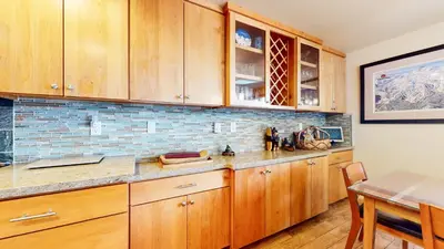 a kitchen with wooden cabinets and a dining table at Sierra Megeve #7 Condo in Mammoth Lakes