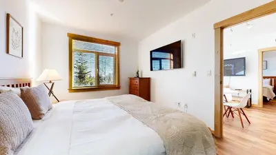 a white bedroom with a bed and a desk at Sunstone #109 Condo in Mammoth Lakes