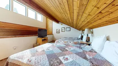 a bedroom with a large bed with a wooden ceiling at Snowflower #49 Condo in Mammoth Lakes