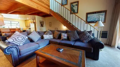 a living room with a couch and a staircase at Snowflower #74 Condo in Mammoth Lakes