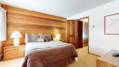 a bedroom with a large bed with wooden walls at Snowflower #68 Condo in Mammoth Lakes