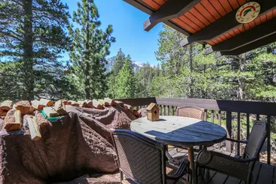 a table and chairs on a deck with trees at Mammoth West #143 Condo in Mammoth Lakes