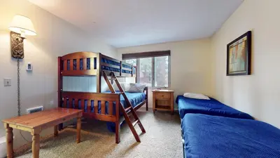 a room with two beds and a table and a bed and a desk at Chateau De Montagne #24 Condo in Mammoth Lakes