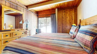 a bedroom with a bed and a wooden wall at Condo de los Pinos #30 in Mammoth Lakes
