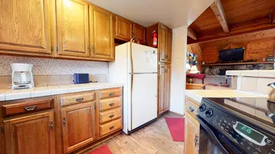 a kitchen with wooden cabinets and a white refrigerator at Snowflower #81 Condo in Mammoth Lakes