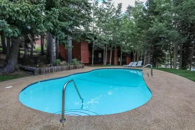 a swimming pool with a bench in front of a building at Mammoth West #101 Condo in Mammoth Lakes
