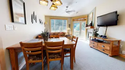 a dining room with a table and chairs and a television at Sunstone #208 Condo in Mammoth Lakes