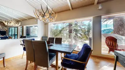 a dining room with a table and chairs and windows at Mammoth West #137 Condo in Mammoth Lakes