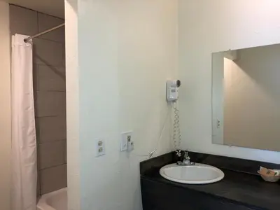 a bathroom with a sink and a mirror and a tub at Cedar Inn & Suites in South Lake Tahoe