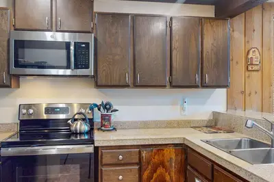 a kitchen with wooden cabinets and a stove and a sink at Mammoth Ski & Racquet Club #131 in Mammoth Lakes